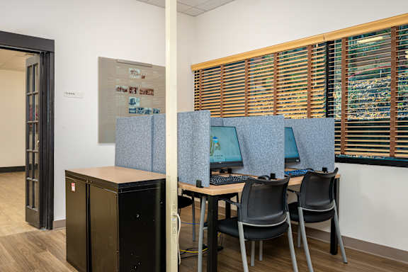 A room with a desk, chairs and a computer.
