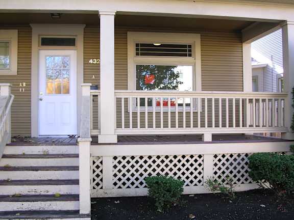 A house numbered 432 with a white door and a window with a red curtain.