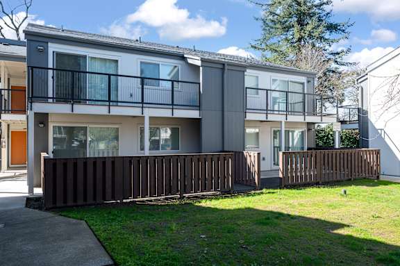 A modern two-story apartment building with a balcony and a fence.