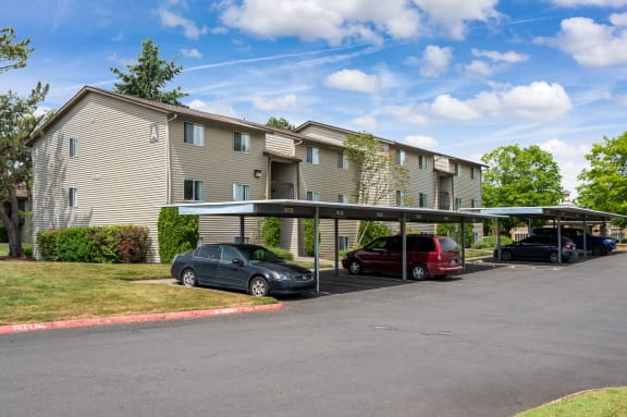 a large apartment building with a parking lot and cars parked under the awning