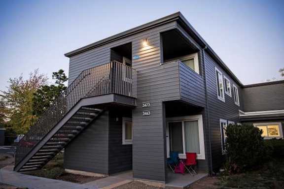 A grey two story house with a balcony on the upper floor.