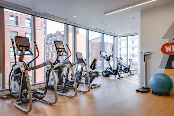A gym with treadmills, exercise bikes and a large ball.