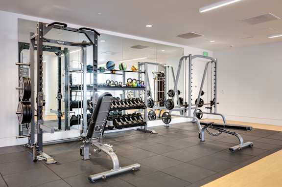 A gym with a variety of equipment including weights and weight machines.