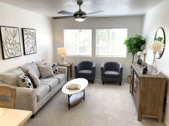 a living room with a couch and chairs and a ceiling fan