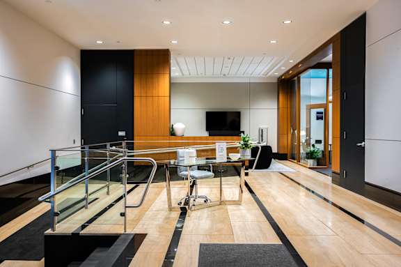 A modern living room with a glass staircase leading to the upper floor.