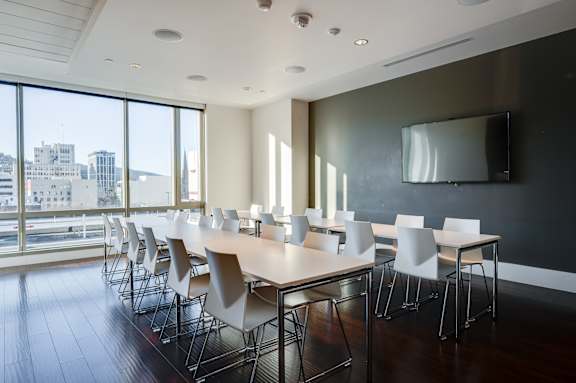 A conference room with a long table and chairs with a city view through the windows.