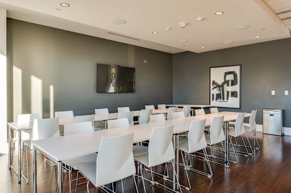 A conference room with white chairs and a long table.
