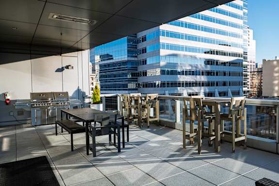 A rooftop patio with tables and chairs overlooking a cityscape.