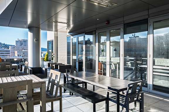 A patio with tables and chairs overlooking a cityscape.
