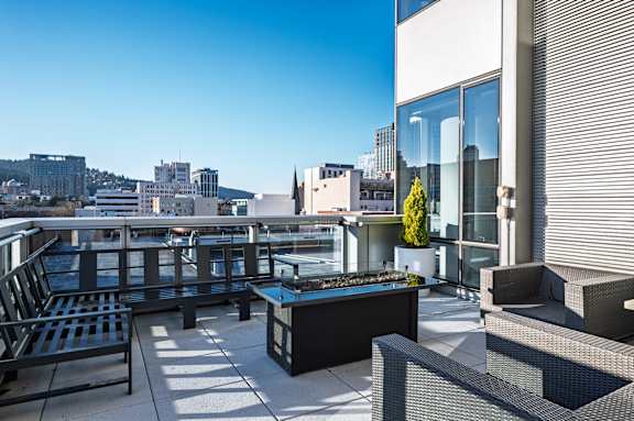A patio with black furniture and a view of the city.