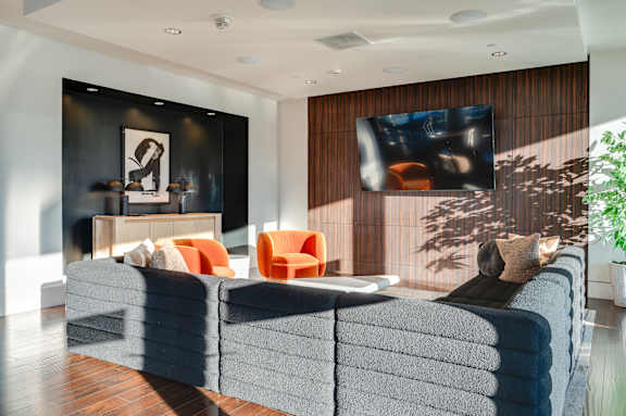 A living room with a grey couch and a television on the wall.