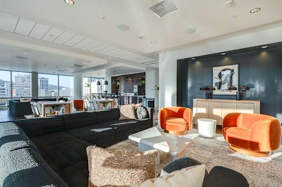 A modern living room with a black couch and orange chairs.