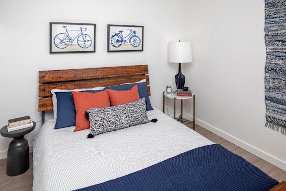A bed with a wooden headboard and a white comforter with a blue blanket on it.