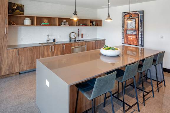 A modern kitchen with a large island and chairs.