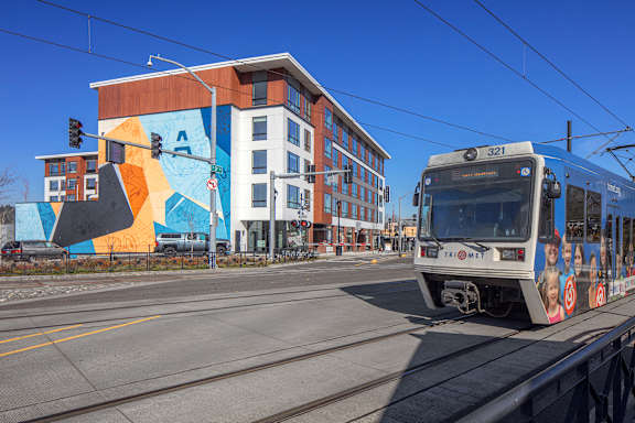 A train is on the tracks in front of a building with a mural.