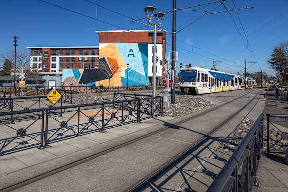 A train is on the tracks in front of a colorful building.