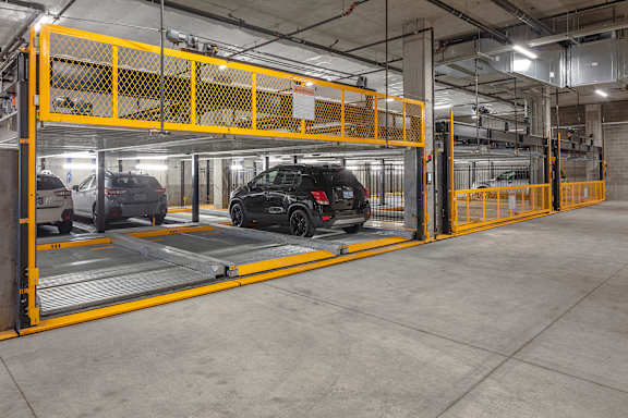 A parking garage with a black car parked in a spot.