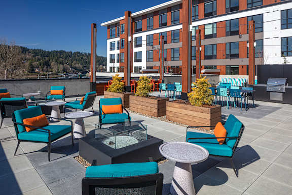 A patio with blue chairs and a table with a glass top.
