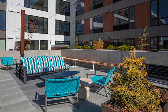 A patio with a blue cushioned chair and a table.