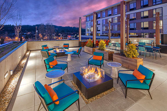 A patio with a fire pit and chairs.