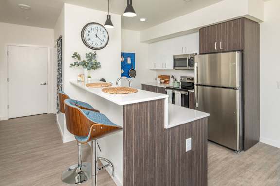 A modern kitchen with a bar stool and a clock on the wall.