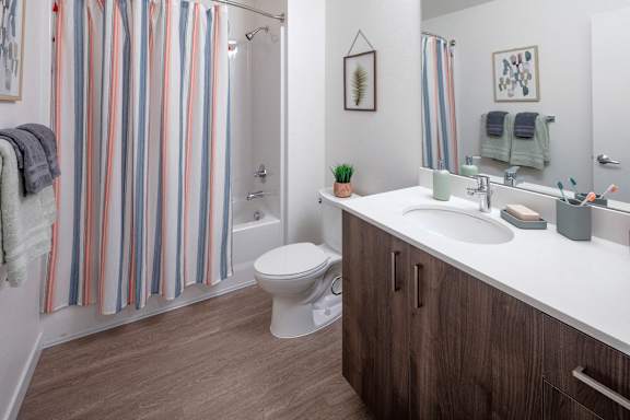 A bathroom with a toilet, sink, and striped shower curtain.