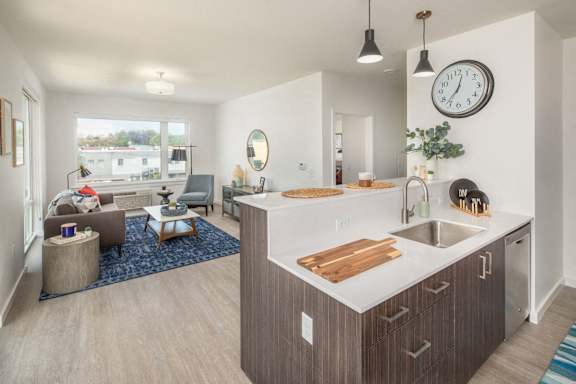 A modern kitchen with a large island and a living room with a couch and a chair.