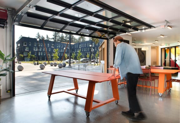 a man playing ping pong on a table in a room with a pool table and a