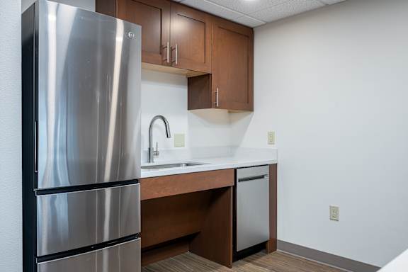 A kitchen with a stainless steel refrigerator and wooden cabinets.