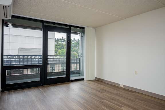 A room with a sliding glass door and wooden flooring.