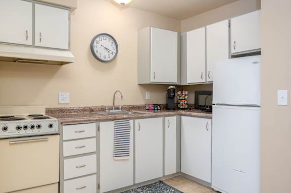 A kitchen with a white refrigerator, a white stove, and a white oven.
