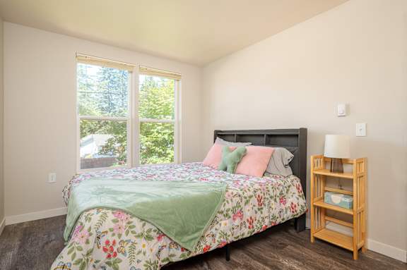 A bedroom with a bed, a nightstand, and a window.