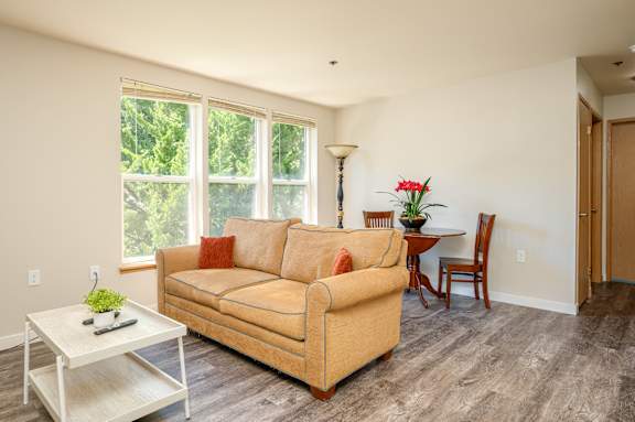 A living room with a tan couch, a white coffee table, and a lamp.