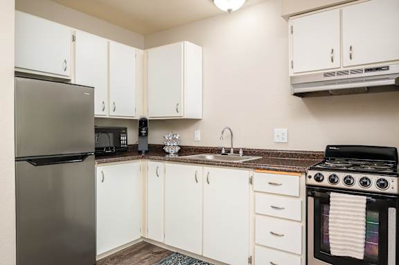 A kitchen with white cabinets and a black stove.