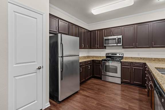 A kitchen with brown cabinets and a stainless steel refrigerator.