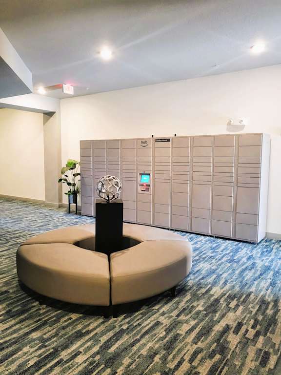 A round sofa in the middle of a room with a wall of lockers behind it.