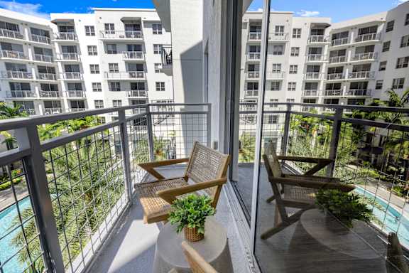 A balcony with two chairs and a table with a potted plant on it.