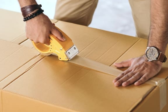 a man taping a cardboard box closed
