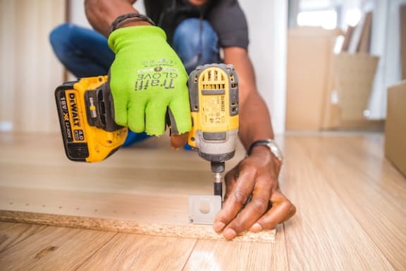 a man using a drill on a piece of wood-style flooring