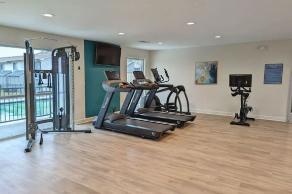 a room with two treadmills and a tv on the wall  at Huntsville Landing Apartments, Huntsville