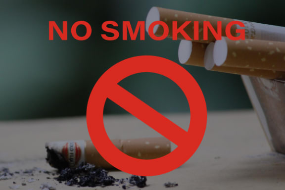 a no smoking sign sitting on top of a pile of cigarettes
