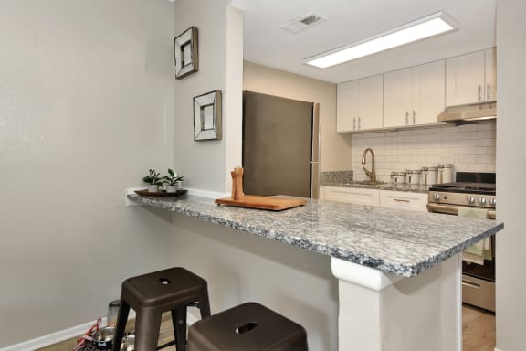 Oasis kitchen with a granite breakfast bar and two stools