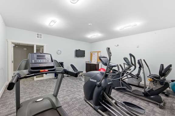 A room with a treadmill, stationary bike, and other exercise equipment.