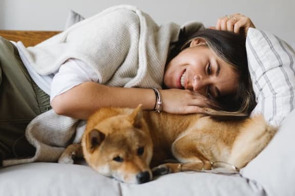 a woman laying on a bed with a dog