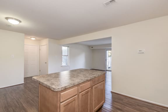 a kitchen with an island and a living room in the background