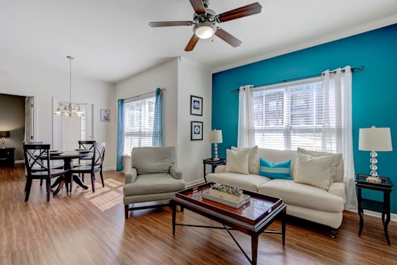 A living room with a white couch, a coffee table, and a dining table at Ethan Pointe Apartments, North Carolina, 27215