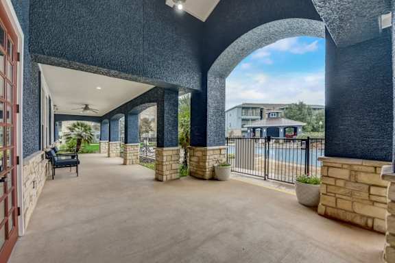A patio area with a pool and a building in the background.