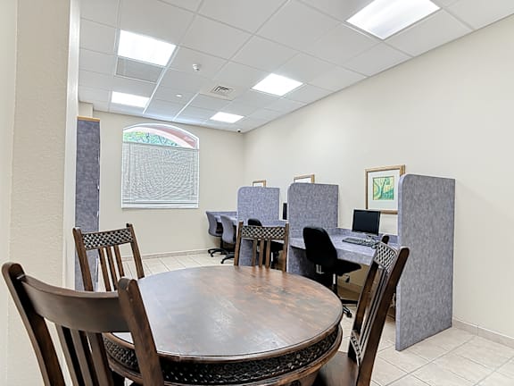 A business center with a table surrounded by chairs.