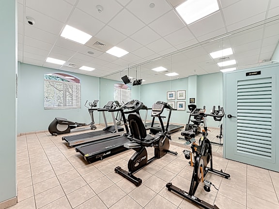 A gym with treadmills, exercise bikes, and a weight bench.