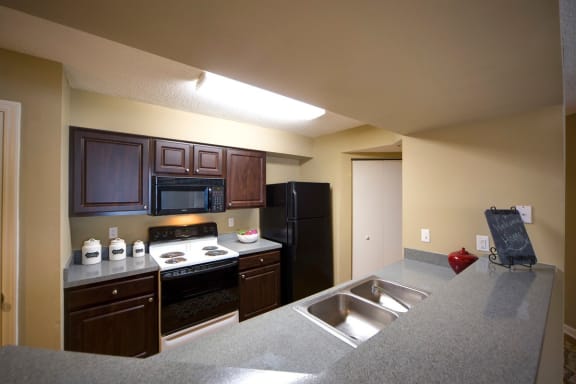kitchen with built-in microwave, refrigerator, cooking range, dark cabinetry and double-basin sink